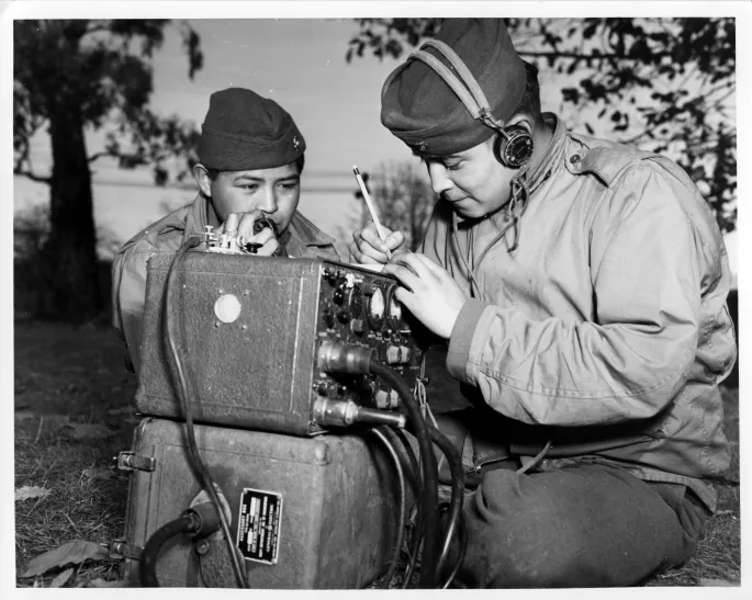 Photograph of Navajo Code Talkers Preston Toledo and Frank Toledo relay orders over a field radio in the South Pacific. (Photo source: https://unwritten-record.blogs.archives.gov/2020/12/01/navajo-code-talkers/)